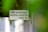 A sign attached to a door or wall states 'NO ADVERTISING MATERIAL ACCEPTED Thank You!' with a background partially obscured by green leaves, creating a soft focus effect.