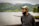 man in gray hoodie wearing white cap standing near body of water during daytime