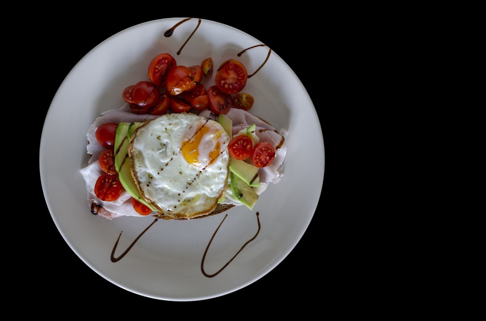 rodajas de tomate y verdura de hoja verde en plato de cerámica blanca