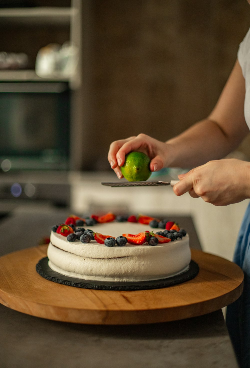 person holding white cake with strawberry on top