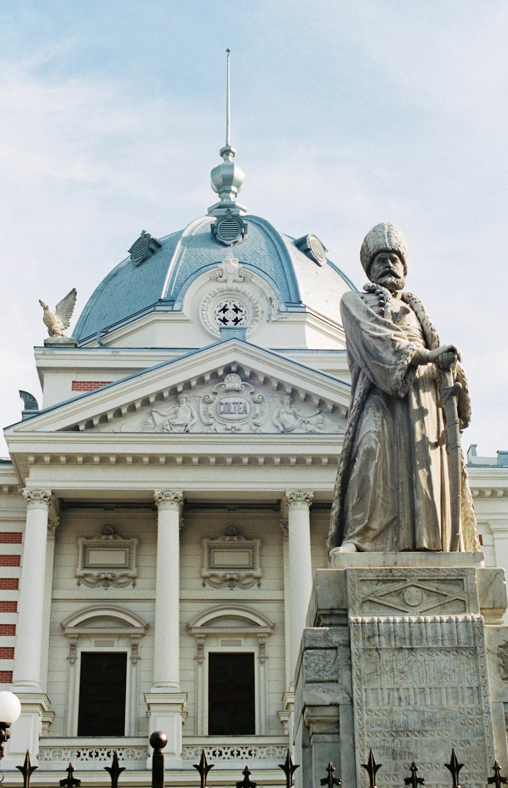 man in robe statue near blue and white concrete building during daytime