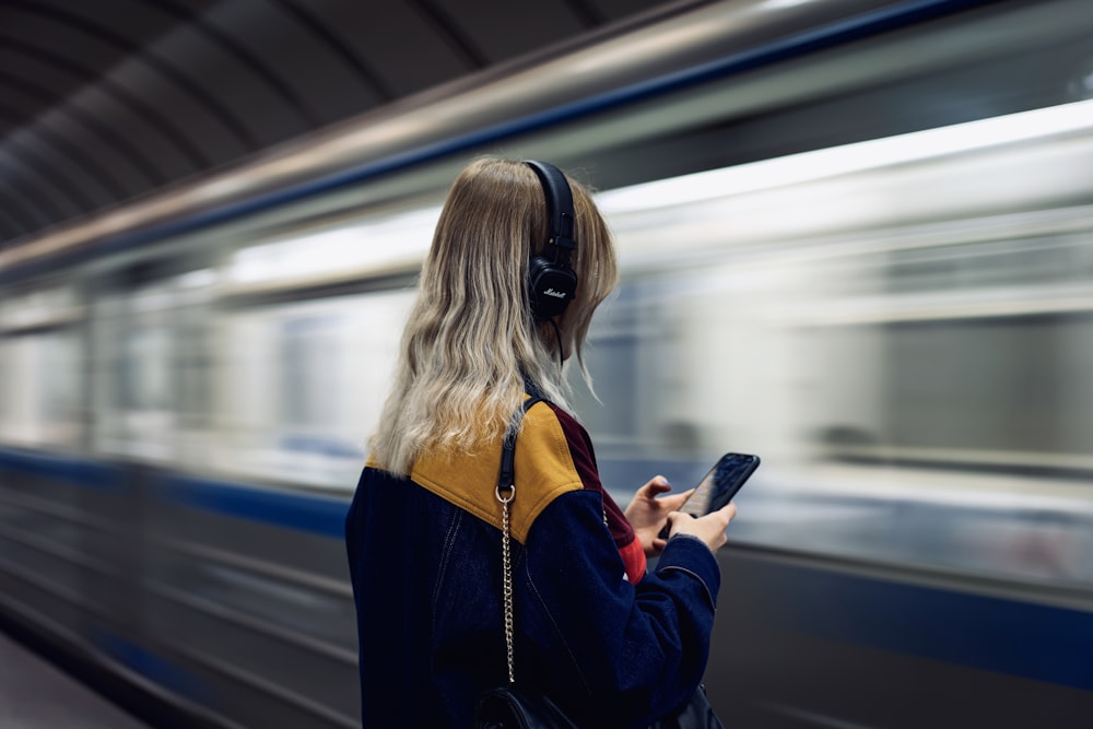 mulher na jaqueta preta que segura o smartphone