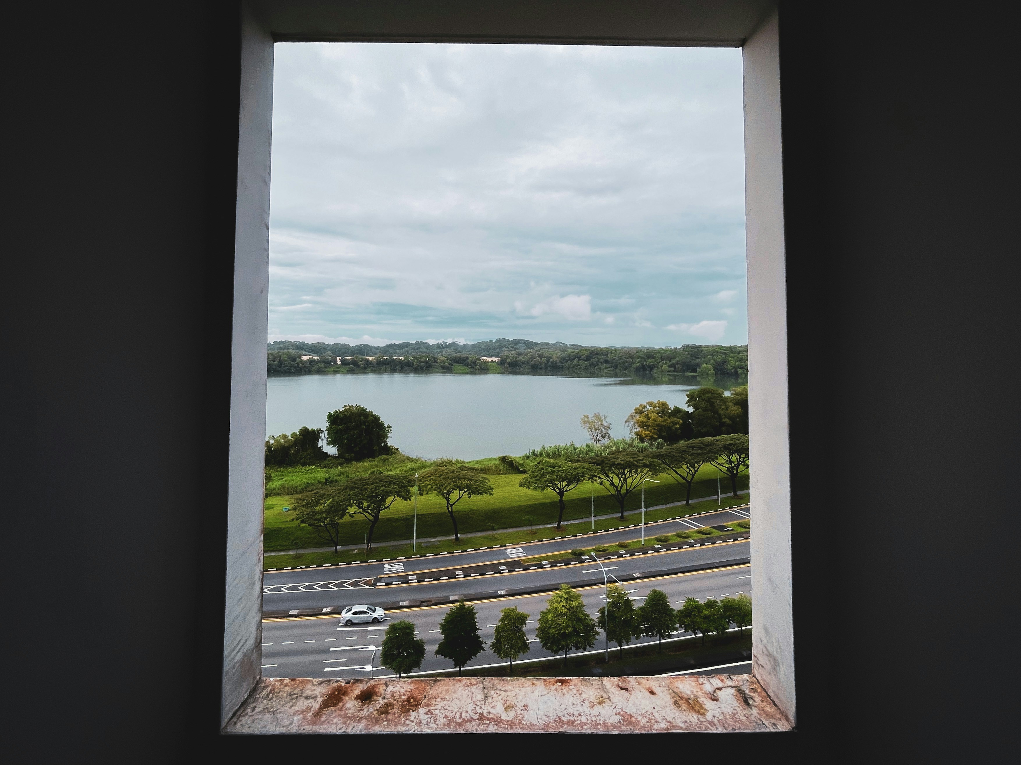 A white car drives on a road near a lake.