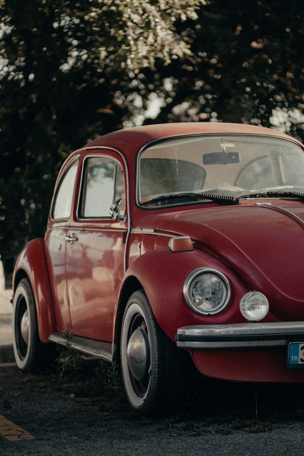 red volkswagen beetle parked on the side of the road