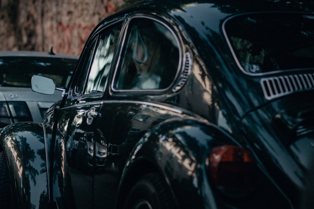 black volkswagen beetle parked on brown soil during daytime