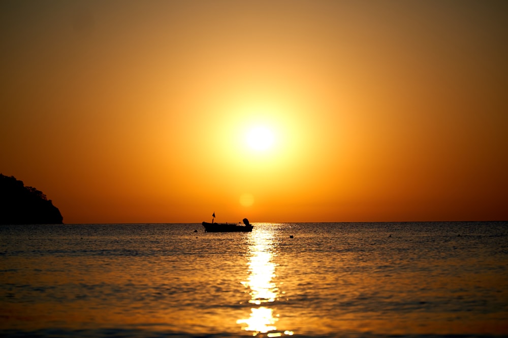 silhouette of person riding on boat on sea during sunset