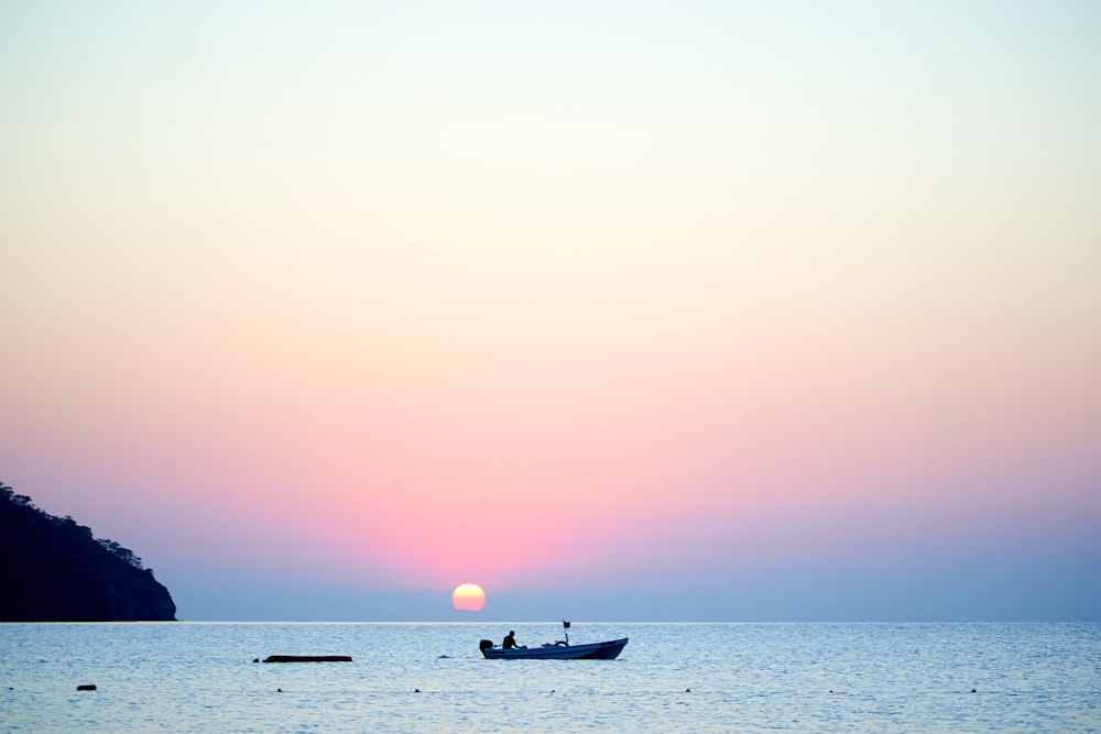 夕暮れ時の海上のボートのシルエット