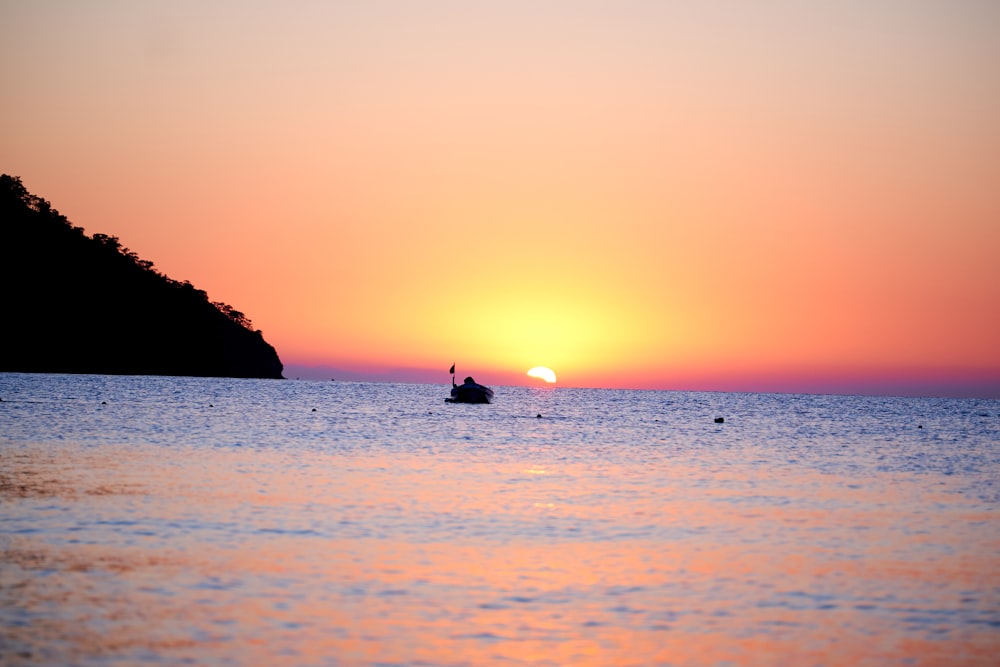 silhouette of person riding on boat on sea during sunset