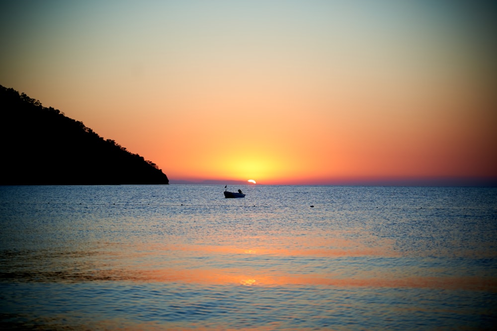 silhouette of boat on sea during sunset