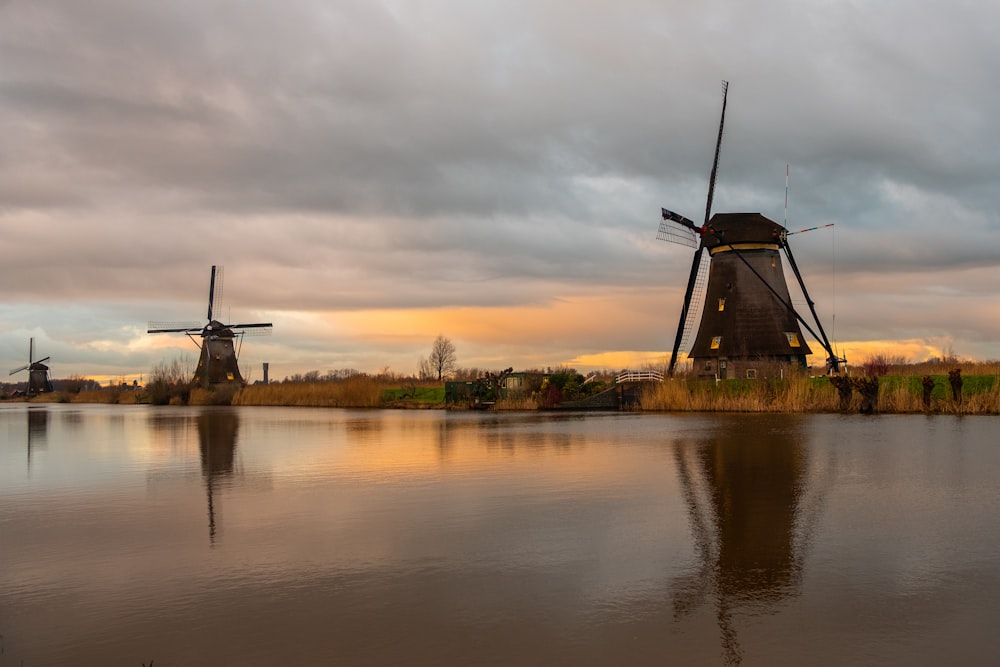 windmill near body of water during sunset