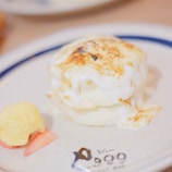 Anime drawing of a sizzling okonomiyaki pancake topped with sauce and mayo.