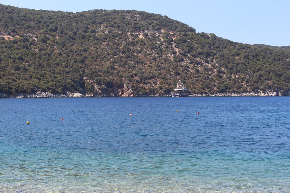 people riding boat on sea near green mountain during daytime