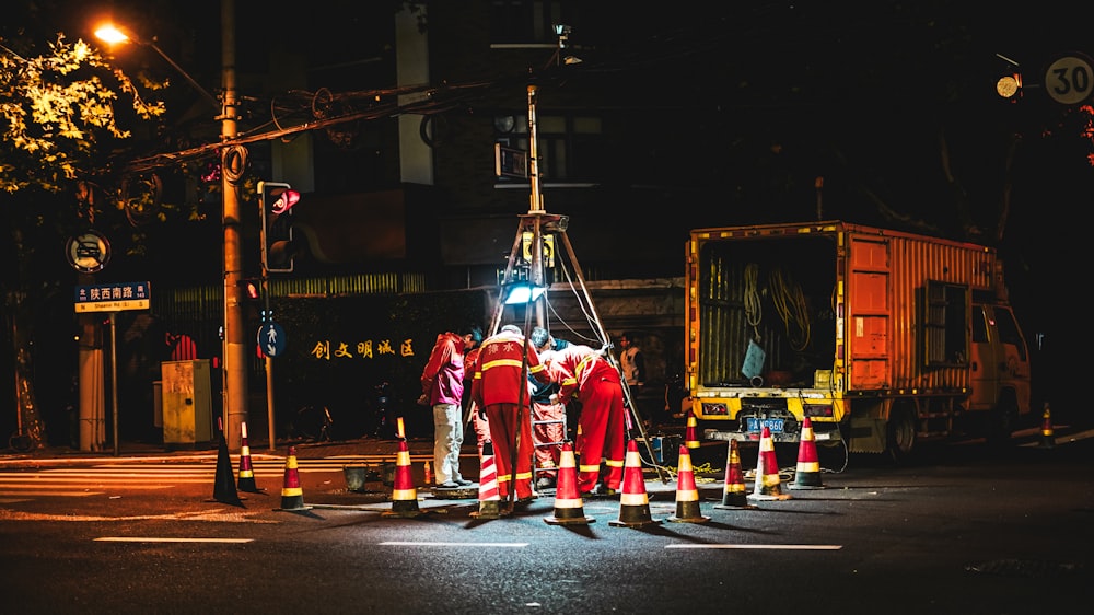 people in red and yellow suit standing on gray concrete road during nighttime