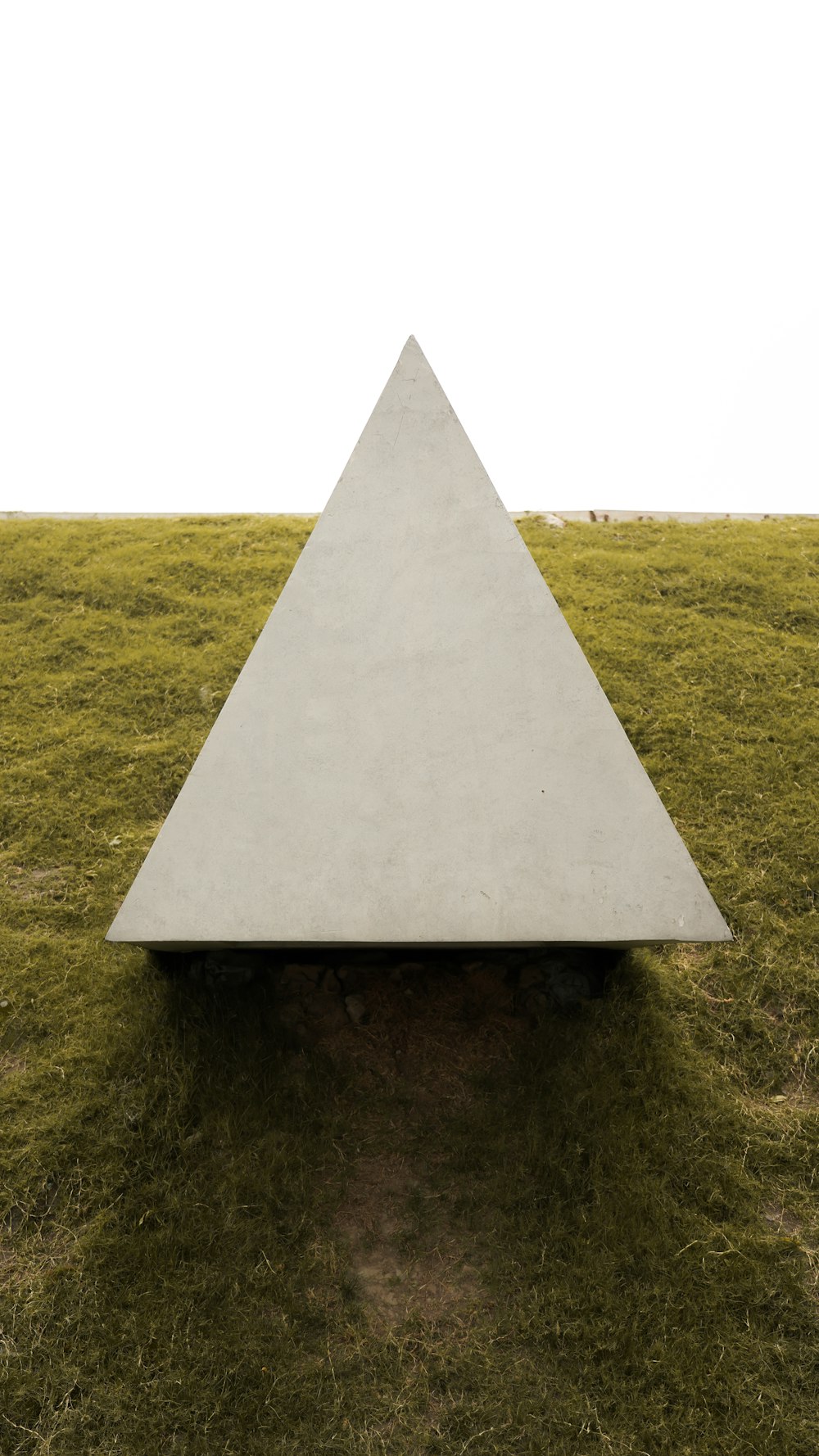 緑の芝生の上の灰色のコンクリートピラミッド