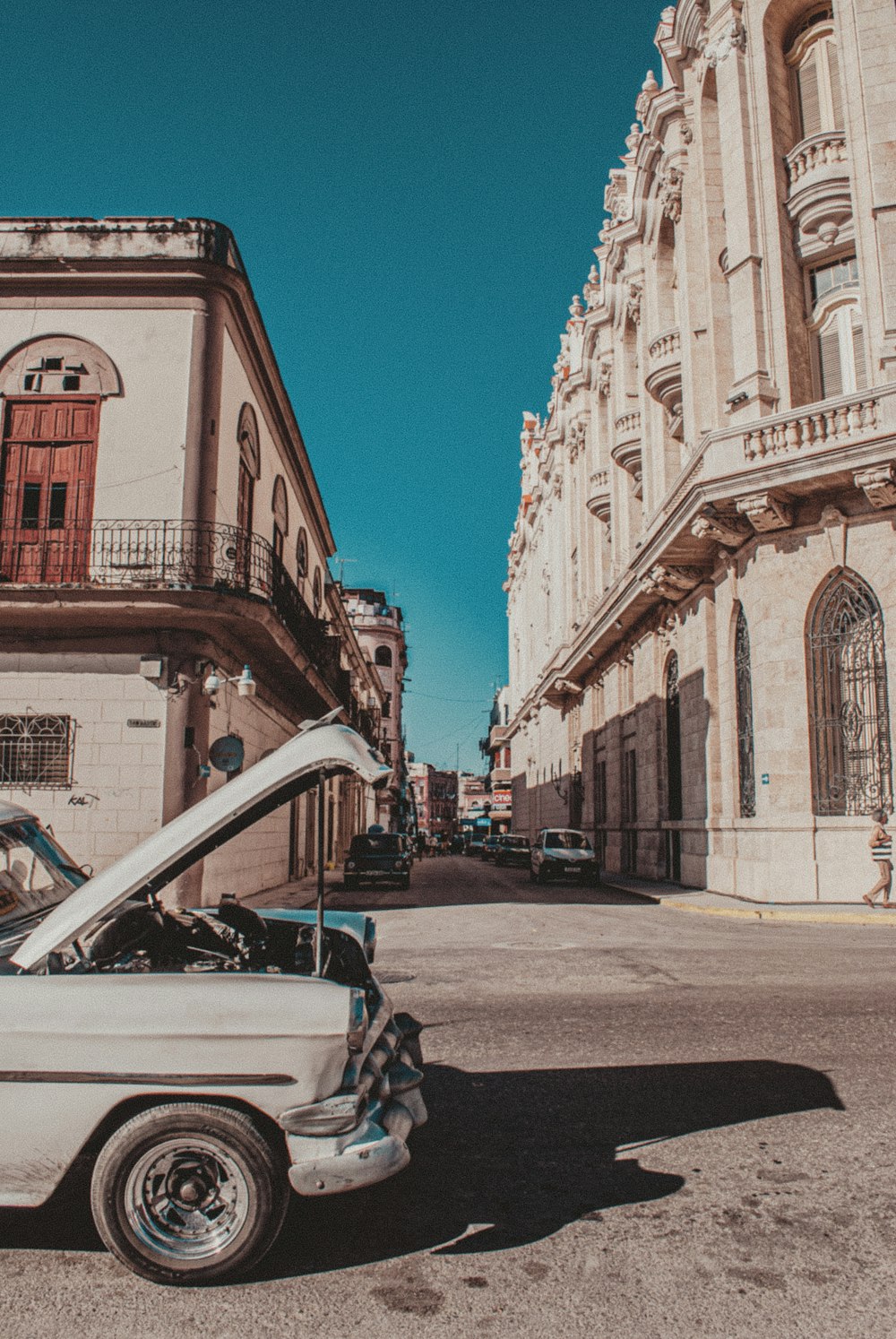 carro branco estacionado ao lado do edifício de concreto marrom durante o dia