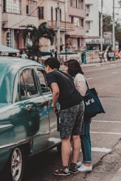 man and woman standing beside green car during daytime