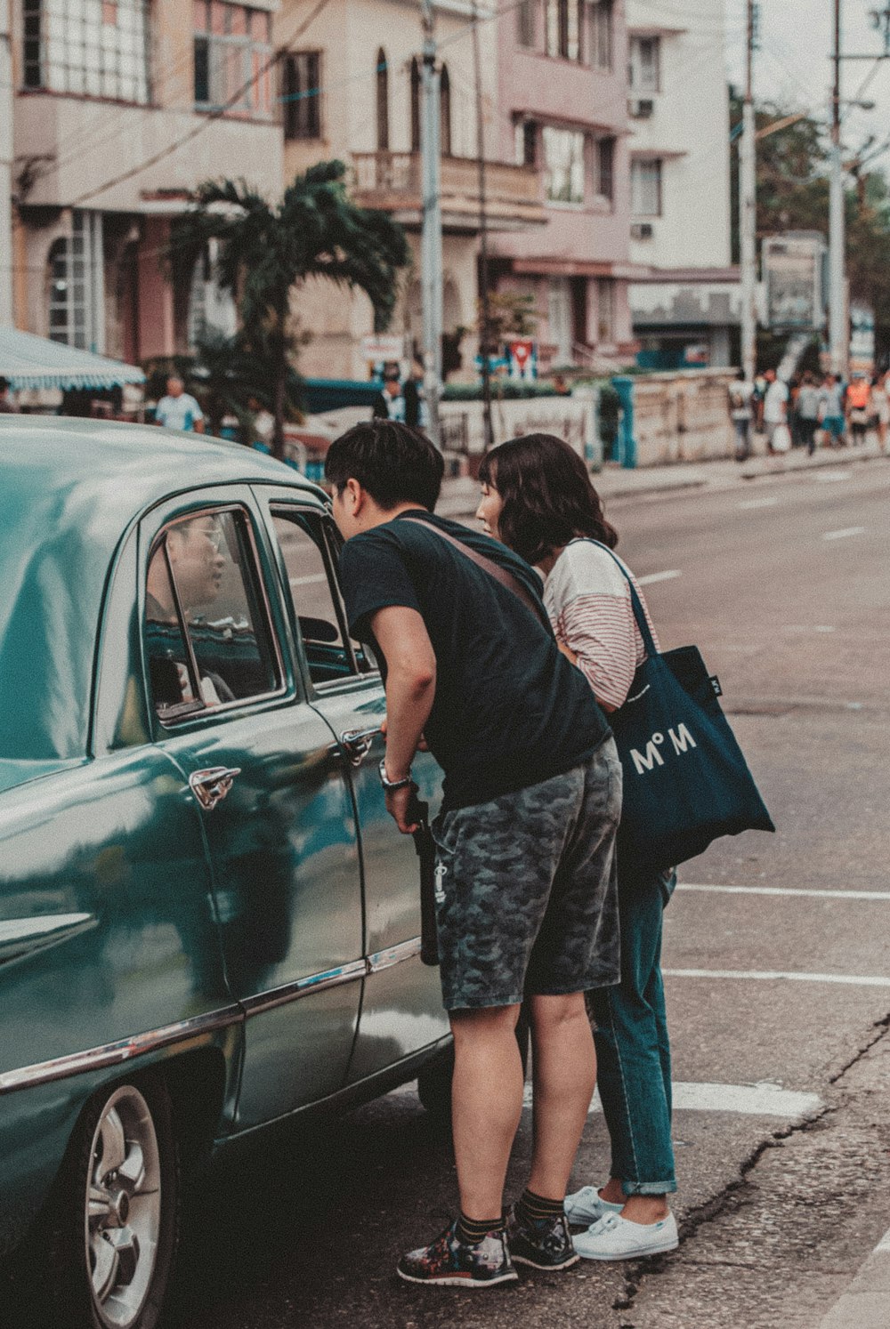 man and woman standing beside green car during daytime