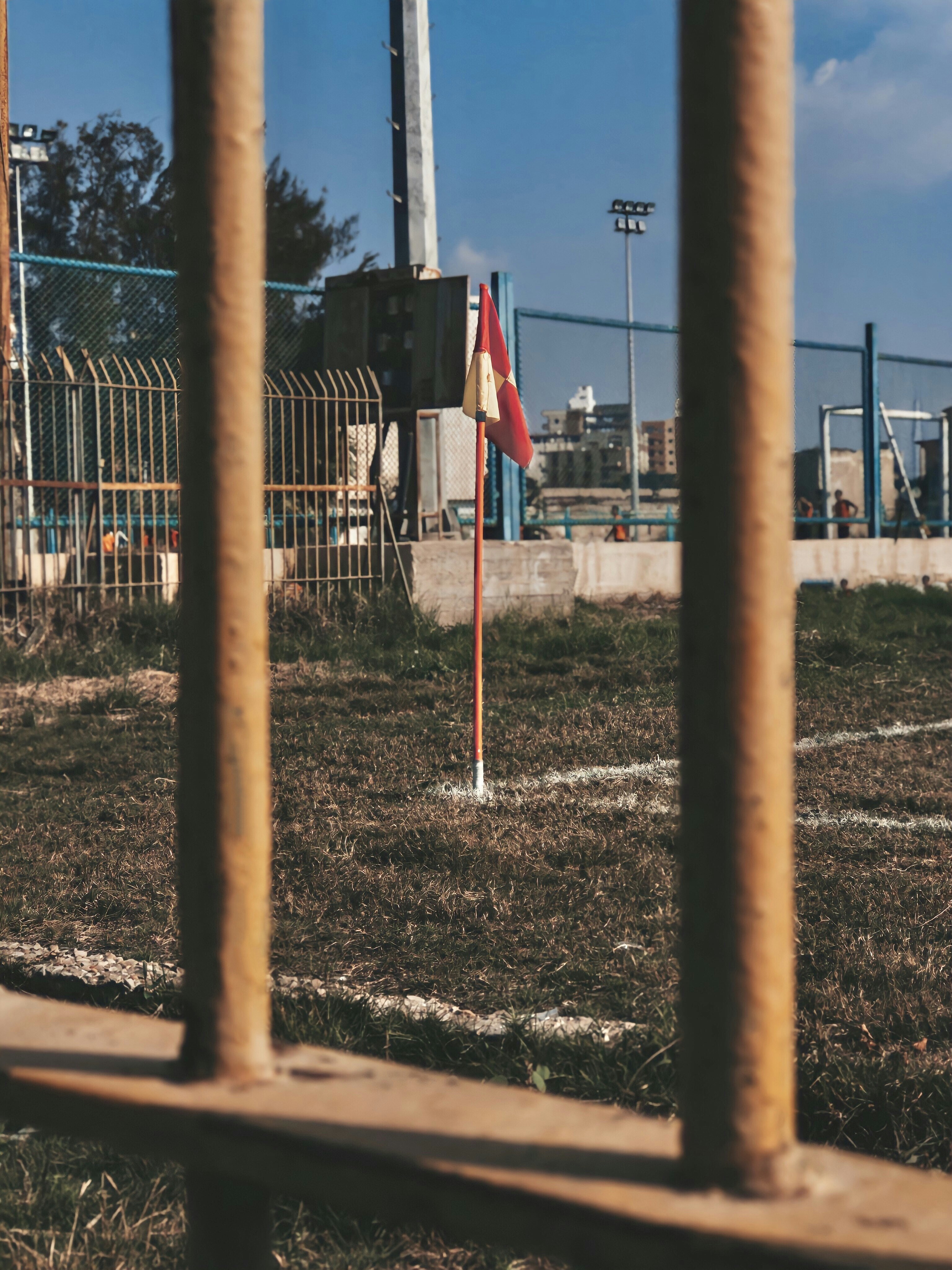 brown metal fence near red and white building during daytime
