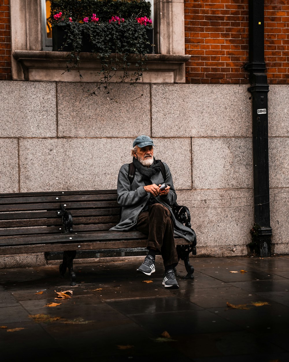man in black jacket sitting on brown wooden bench