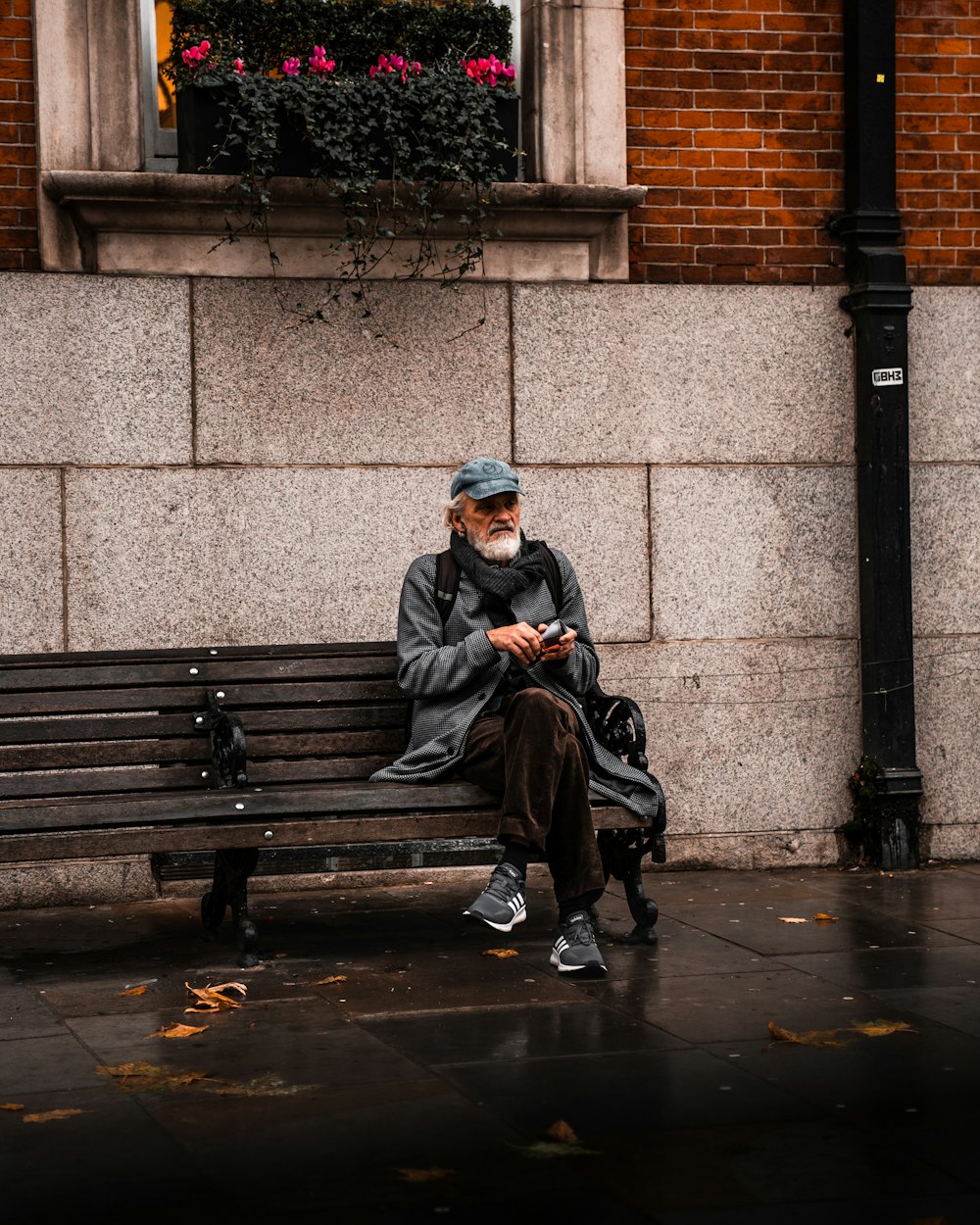 Homme en veste noire assis sur un banc en bois brun