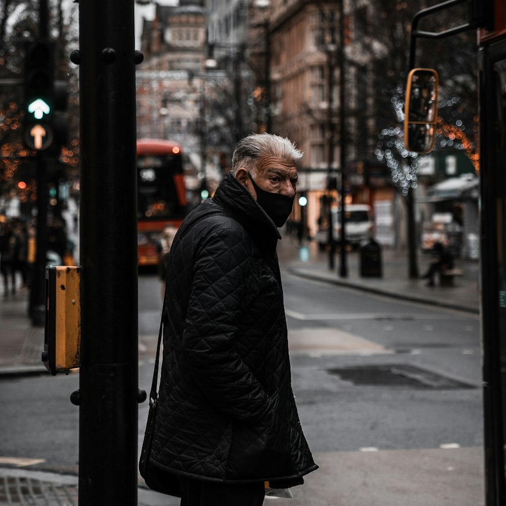 man in black jacket standing on sidewalk during daytime