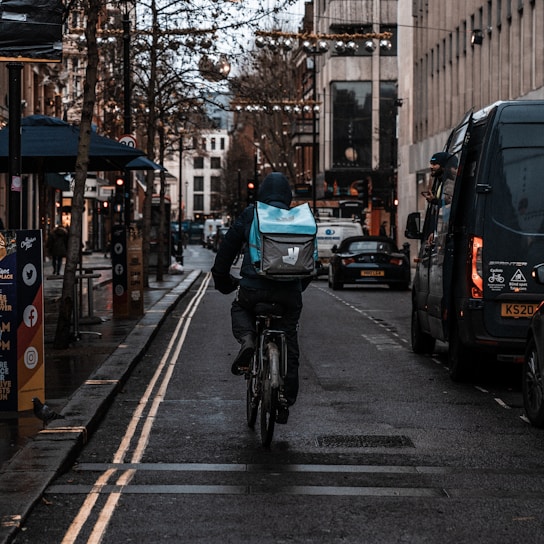 A delivery person riding a bicycle through a city street.