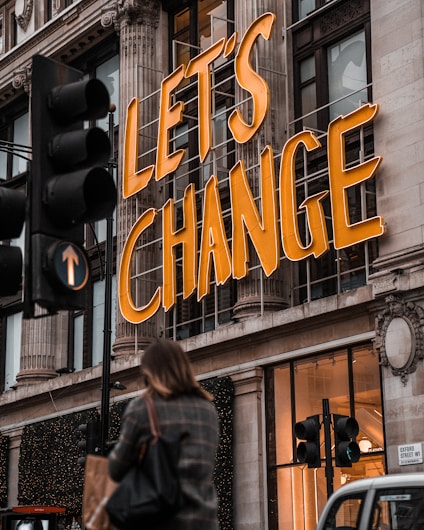 a woman walking past a building with a sign that says let's change