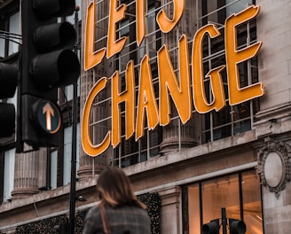 a woman walking past a building with a sign that says let's change