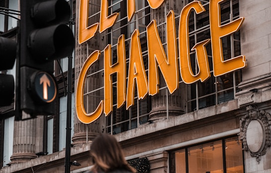 a woman walking past a building with a sign that says let's change