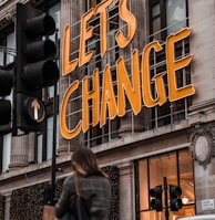 a woman walking past a building with a sign that says let's change