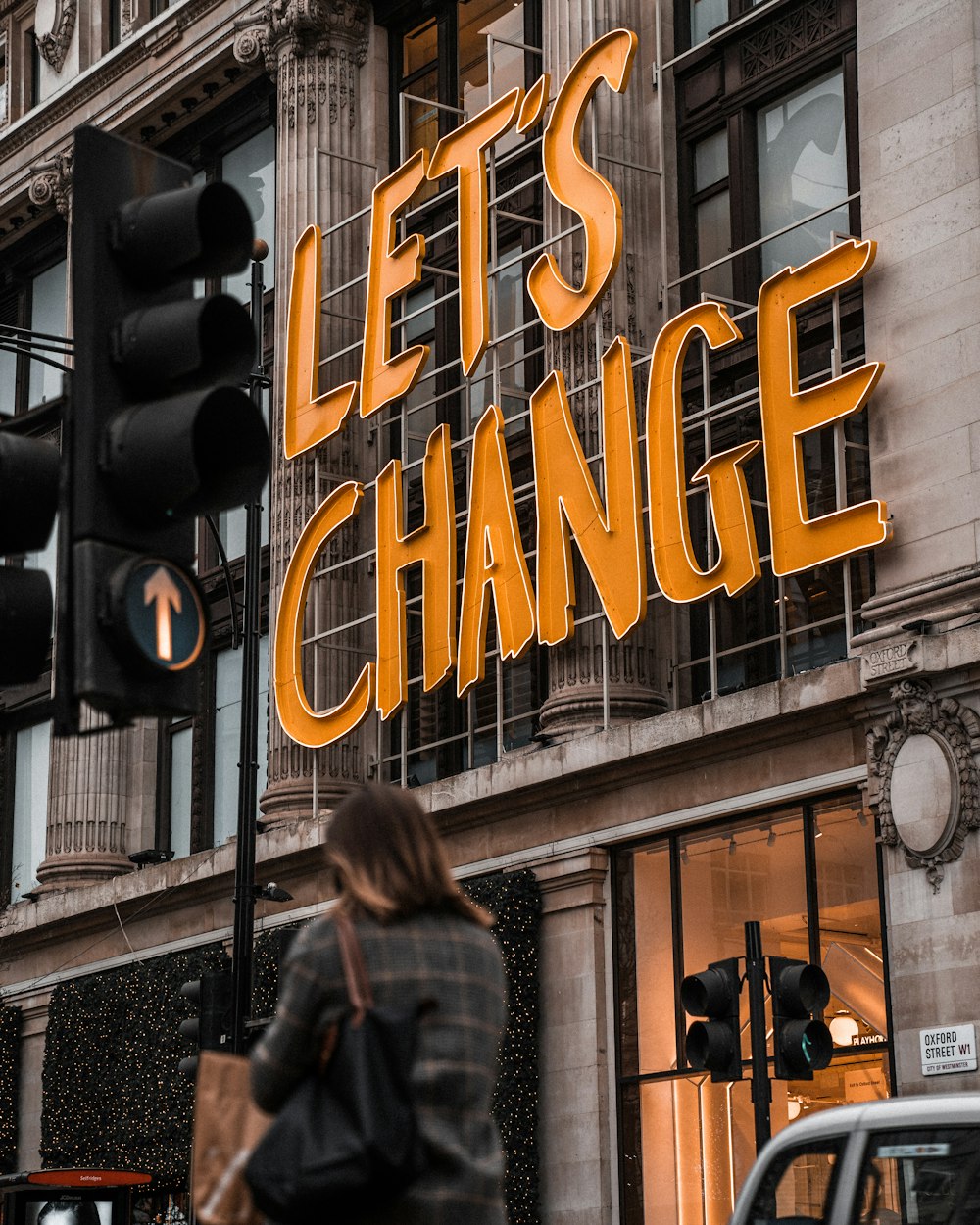 Una mujer pasando por un edificio con un letrero que dice Let's Change