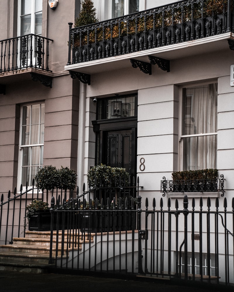 Restored white-stucco London Georgian period townhouse facade with tall sash windows and wrought-iron railings