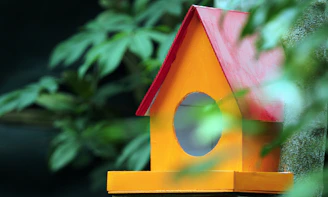 A vibrant handmade birdhouse painted in bright orange and green hues.