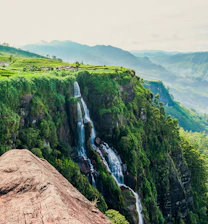 person in blue jacket and blue denim jeans standing on brown rock mountain during daytime