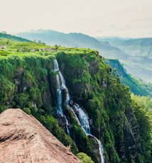 person in blue jacket and blue denim jeans standing on brown rock mountain during daytime