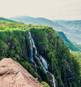 person in blue jacket and blue denim jeans standing on brown rock mountain during daytime
