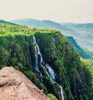 person in blue jacket and blue denim jeans standing on brown rock mountain during daytime