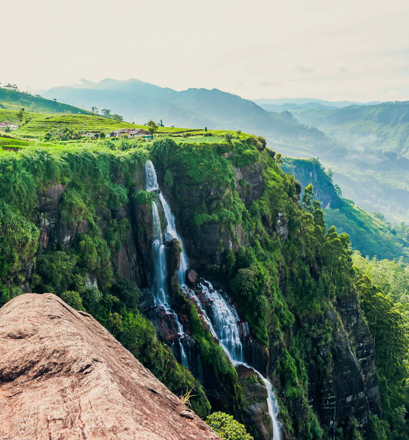 A waterfall falling into a misted hill-country valley