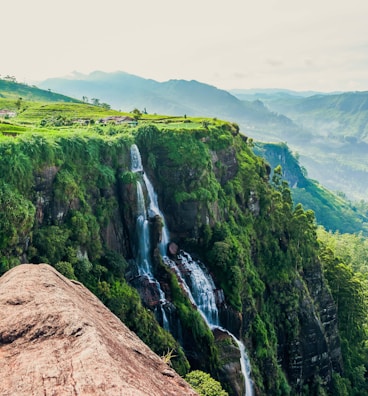person in blue jacket and blue denim jeans standing on brown rock mountain during daytime