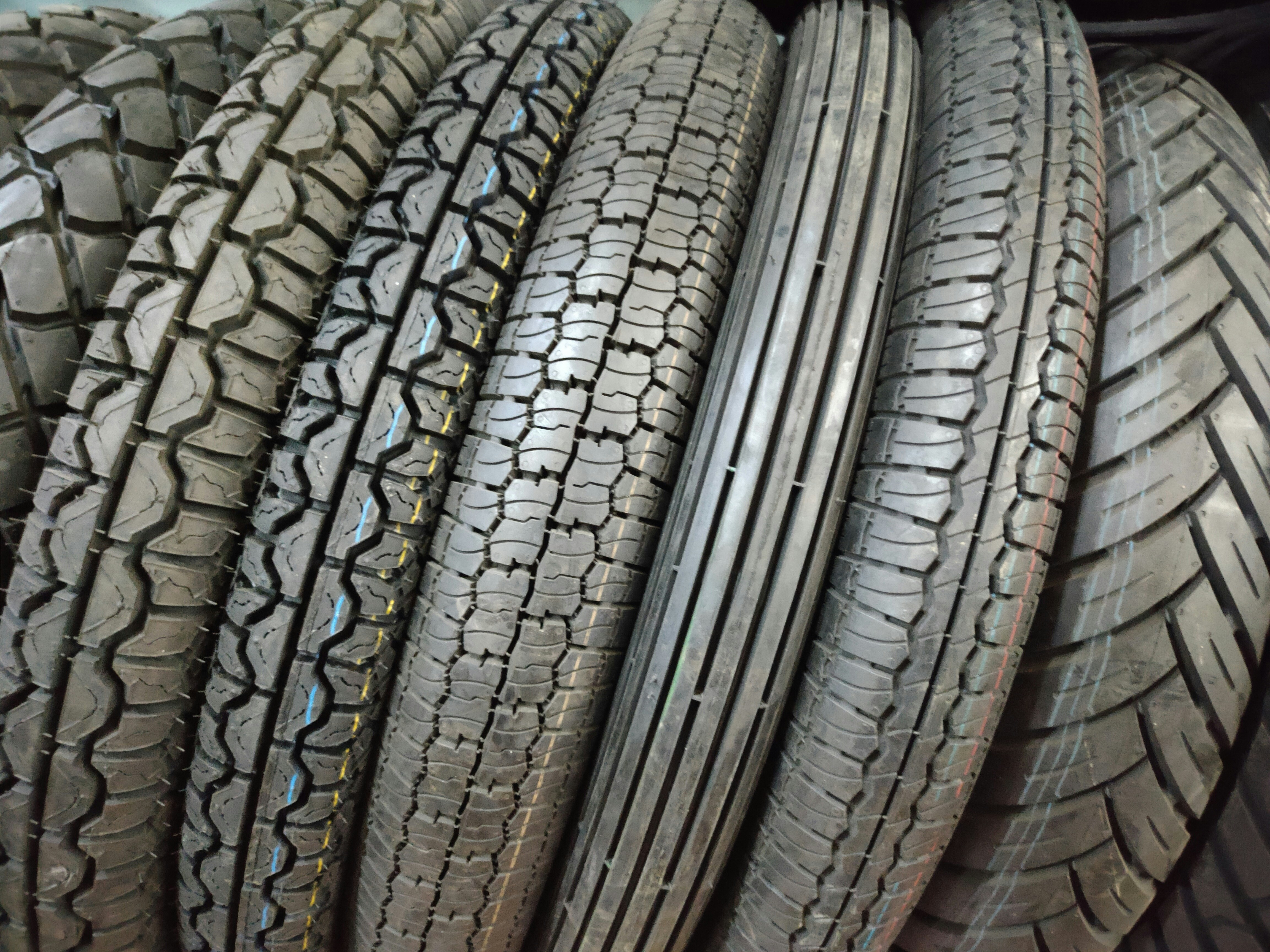 Rows of tires stacked in a tire shop, dark industrial storage area with organized inventory