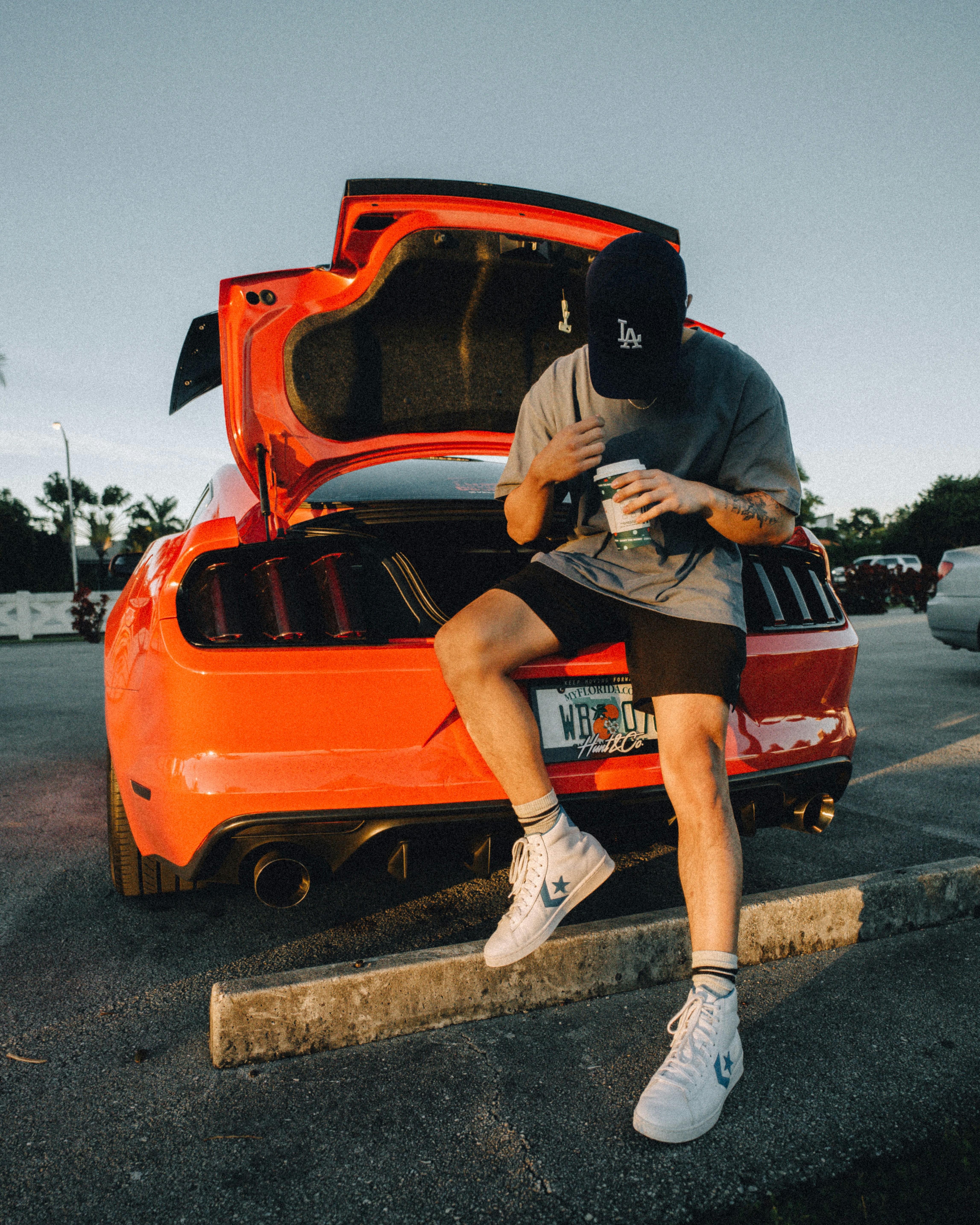 man in black t-shirt and brown shorts sitting on red car