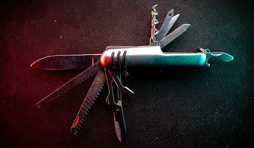 A multi-tool gadget with various fold-out tools displayed on a rustic wooden table.