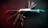 A multi-tool pocket knife is displayed with its various tools extended against a dark background. The knife includes multiple blades, a corkscrew, a saw, and other utility tools. The lighting gives the knife a metallic sheen with subtle hints of red and green reflections.