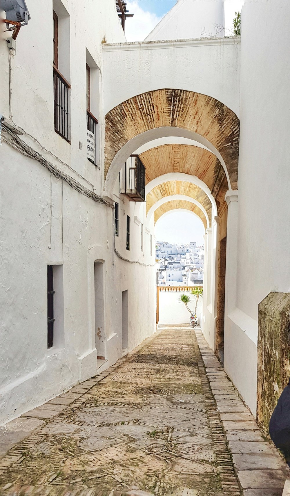 brown wooden pathway between white concrete buildings during daytime