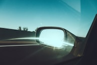 Side view of a sleek, polished car mirror reflecting a clear sky.