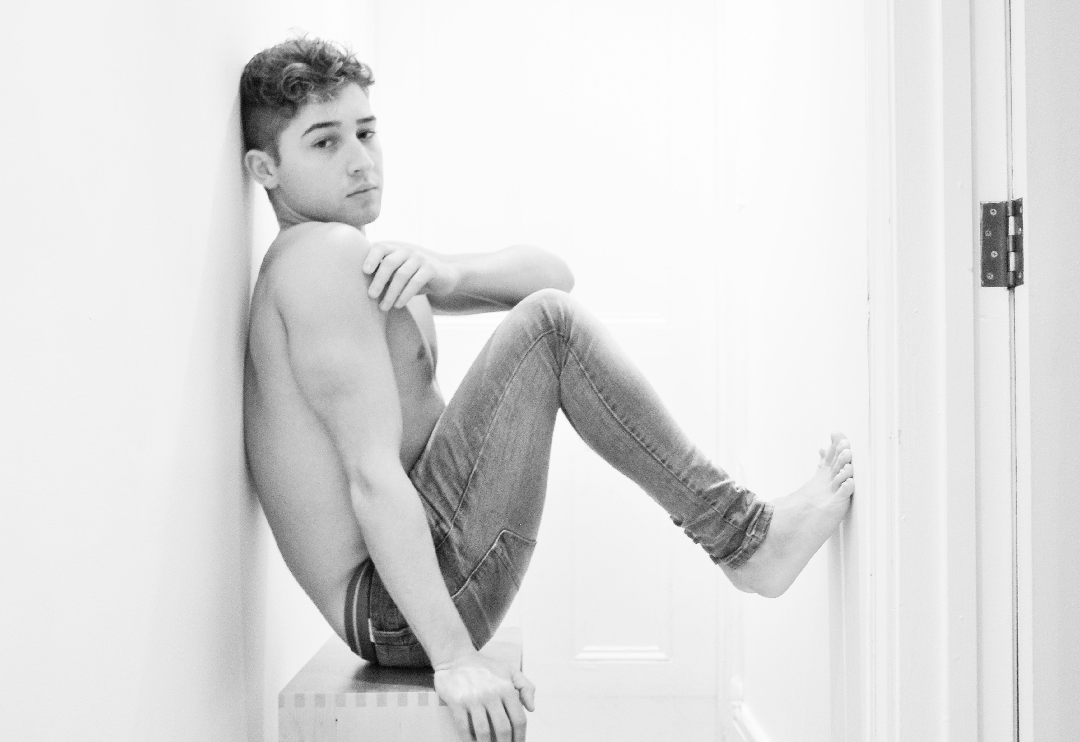 topless boy sitting on floor