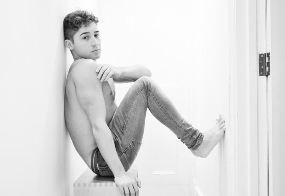 topless boy sitting on floor