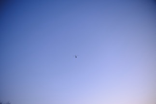 A helicopter flying over an open airfield during clear weather.