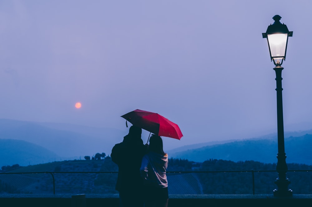 person in black jacket holding umbrella standing on dock during daytime