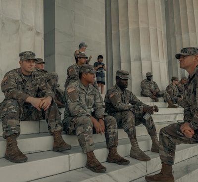 men in camouflage uniform standing near white wall